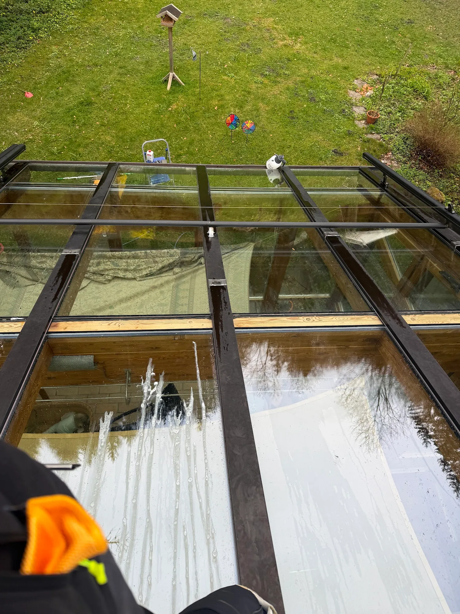 Reinigungskraft bei der manuellen Reinigung von Glasfeldern auf einem Holzhaus