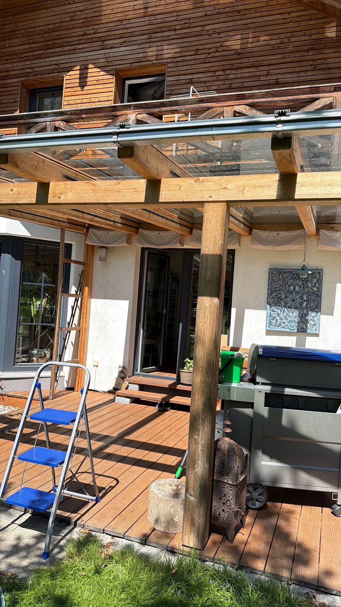 Gepflegte Holzterrasse mit gereinigter Glasüberdachung am Garten
